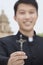Young Priest Holding Crucifix, Looking at Camera, Focus On Foreground