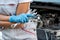 Young professional female mechanic inspects under the hood of a car in an auto repair shop