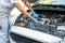 Young professional female mechanic inspects under the hood of a car in an auto repair shop