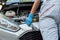 Young professional female mechanic inspects under the hood of a car in an auto repair shop