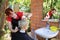 Young professional hairdresser makes haircut to woman in front of mirror in the yard outdoors