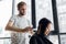 Young professional hip male hairdresser cutting dark hair of client woman at salon.