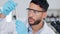 A young professional male scientist inside a laboratory looking at a test tube. Pharmacist student examining liquid in