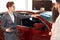 Young professional salesman touching red car