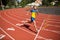 Young professional sportsman running on racetrack of stadium
