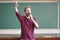 Young professor teacher speaking with the microphone in the lecture hall standing near blackboard