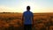 A young prospective farmer walks the wheat field against the backdrop of a sunset at a slow pace. The concept of