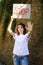 Young protesting woman in white shirt and jeans holds protest sign broadsheet placard with slogan `Stop` for public