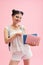 Young reader girl lifts her palm up holding colored books and smiling isolated on vivid pink background