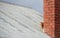 Young red ginger tubby cat sitting behind a chimney exploring the world