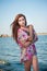 Young red hair girl in multicolored blouse posing on the beach. Sensual attractive woman with long hair, summer shot at sea