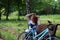 The young red-haired girl with bicycle sat down to have a rest on a shop and to do up let hair down.