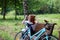 The young red-haired girl with bicycle sat down to have a rest on a shop and to do up let hair down.