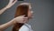 Young red-haired girl combing her hair.