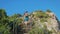 Young red-haired traveler girl with a cowboy hat and a backpack climbs stairs in a mountainous area.