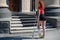 Young red-haired woman with ankle injury climbs stairs on crutches.