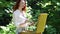 Young red-haired woman with an easel in the forest