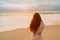 Young red-haired woman with flying hair on the ocean, rear view