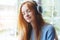 Young red haired woman with headphones listening to music at home, relaxing, enjoying songs, closed eyes, soul music