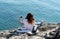 Young red haired woman taking a selfie on the beautiful stone beach near blue sea surface on the sunny day