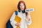Young red head girl wearing backpack holding online banner afraid and shocked with surprise and amazed expression, fear and