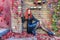 Young Red head gothic woman sitting at the bottom of the brick wall surrounded by autumn leaves and colorful vines