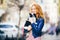 Young redhaired Caucasian woman with freckles on face holds and kisses, hugs, loves black and white shaggy dog of Chihuahua breed.