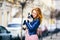 Young redhaired Caucasian woman with freckles on face holds and kisses, hugs, loves black and white shaggy dog of Chihuahua breed.