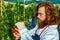 young redhaired ginger bearded man in apron cut bushes in the garden or plantation