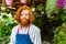 young redhaired ginger bearded man in apron working in the garden or plantation