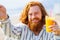 young redhaired ginger bearded man working outdoors in sea cafe with laptop an summer day