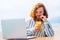 young redhaired ginger bearded man working outdoors in sea cafe with laptop an summer day