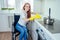 Young redhaired ginger disabled woman in wheelchair wearing yellow ribon gloves and cleaning apartment