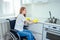 Young redhaired ginger disabled woman in wheelchair wearing yellow ribon gloves and cleaning apartment