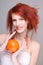 Young redhaired woman with orange in her hands