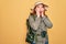 Young redhead backpacker woman hiking wearing backpack and hat over yellow background afraid and shocked, surprise and amazed