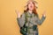 Young redhead backpacker woman hiking wearing backpack and hat over yellow background crazy and mad shouting and yelling with