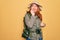 Young redhead backpacker woman hiking wearing backpack and hat over yellow background looking stressed and nervous with hands on