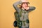 Young redhead backpacker woman hiking wearing backpack and hat over yellow background Smiling cheerful playing peek a boo with