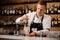 Young redhead barman stirring alcoholic drink with ice cubes