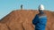 Young redhead bearded caucasian construction worker in blue uniform, protective glasses and hardhat helmet looks at