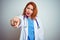 Young redhead doctor woman using stethoscope over white isolated background pointing displeased and frustrated to the camera,