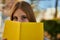 Young redhead girl smiling happy covering face with book at the city