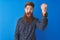 Young redhead irish man wearing floral summer shirt standing over isolated blue background angry and mad raising fist frustrated