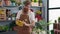 Young redhead man florist wearing gloves standing with arms crossed gesture at flower shop