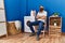 Young redhead man tired waiting for washing machine at laundry room