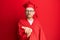 Young redhead man wearing red graduation cap and ceremony robe looking at the camera blowing a kiss with hand on air being lovely