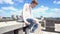 Young redhead man in a white sweatshirt sits on a brick wall on the roof