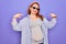 Young redhead pregnant woman expecting baby wearing funny thug life sunglasses looking confident with smile on face, pointing