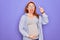 Young redhead pregnant woman expecting baby wearing funny thug life sunglasses pointing finger up with successful idea